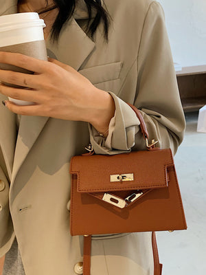 Brown mini crossbody bag in faux leather with gold hardware and a top handle.