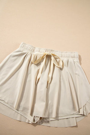 Beige ruffled skort with tie waist detail and elastic waistband.