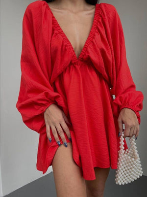 Scarlet ruched V-neck dress with balloon sleeves and a cinched waist, styled with a pearl handbag.