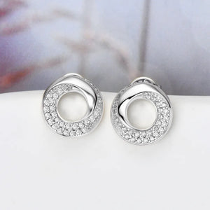 Silver pavé circle stud earrings with a twisted design and sparkling stones.