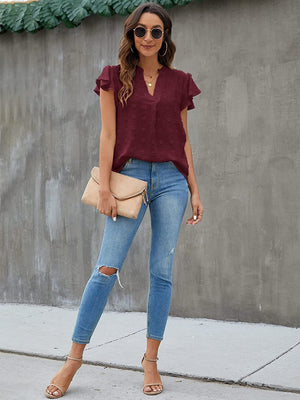 Burgundy textured voile blouse with flutter sleeves and v-neck, styled with jeans.