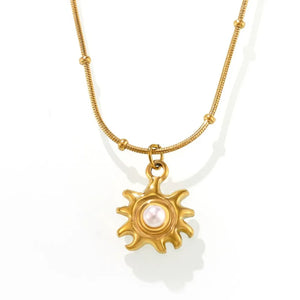 Gold sunburst pendant necklace with pearl detail on a delicate chain with beads.