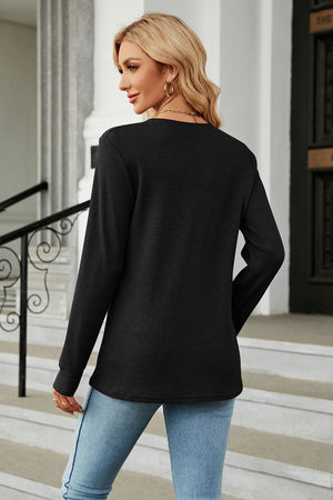 Black waffle knit long sleeve top with a crew neck, styled with jeans.