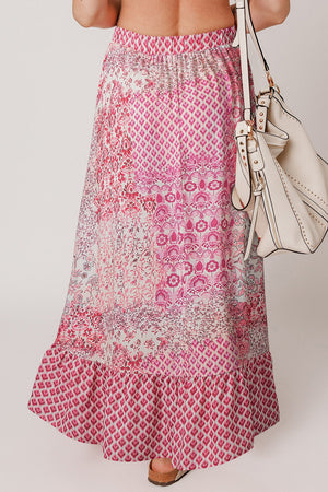 Printed tiered maxi skirt in dusty pink with boho patterns and a ruffled hem.