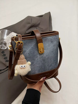 Elegant PU leather bucket bag in blue with brown trim and a fuzzy charm.