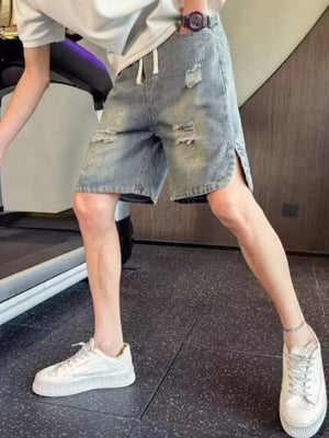Distressed denim shorts with adjustable drawstring, side slits, and raw hem.