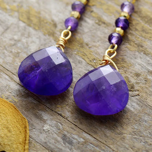 Facet drop amethyst gemstone earrings with gold-plated beads and wire wrapping.