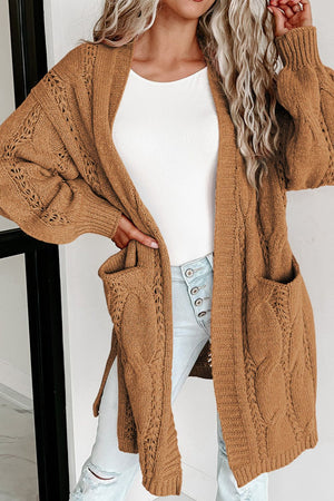 Camel cable knit open-front cardigan with pockets and openwork detail.