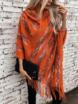 Textured knit hooded cape in terracotta with fringe detail and abstract pattern.