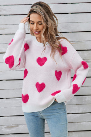 White crewneck sweater with allover hot pink heart appliqué and ribbed cuffs.