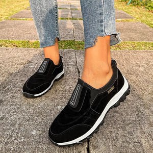 Black suede-like round toe slip-on sneakers with white soles and elastic side panels.