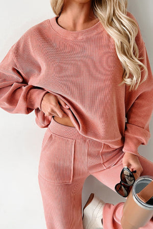 Pink corduroy lounge set with relaxed fit sweatshirt and pants, featuring ribbed texture and pockets.
