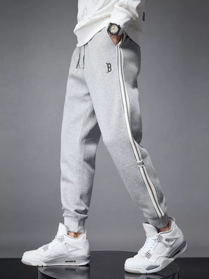 Light gray cotton joggers with side stripes and cuffed ankles.