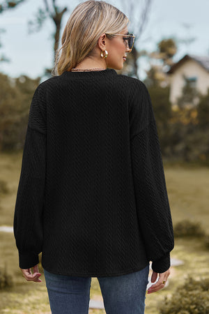 Black cable knit pullover sweater with textured pattern and long sleeves.