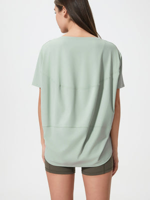 Relaxed fit performance tee in light green with curved seam details on back.