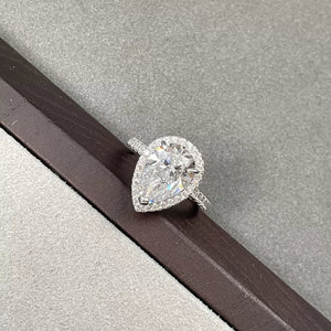 Elegant moissanite teardrop ring in sterling silver with halo setting.