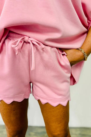Blush pink lounge shorts with drawstring and scalloped hem.