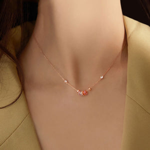 Rose gold necklace with a fine chain and a cluster of small, colorful rings and clear crystals.