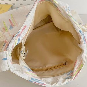 Ivory slouchy shoulder bag with colorful embroidered detail and beige lining.