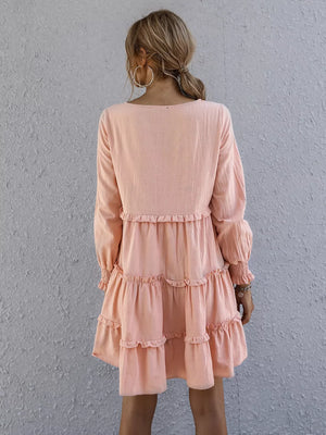 Apricot ruffled mini dress with long sleeves and tiered skirt detail.