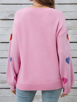 Pink acrylic knit sweater with bubble sleeves and scattered heart motifs.