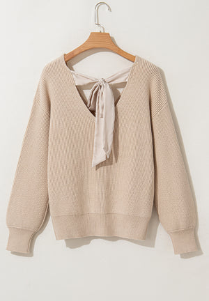 Beige ribbed knit sweater with V-neck and satin bow detail at the back.