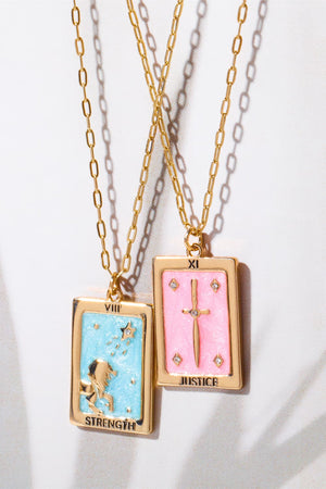 Tarot card pendant necklaces in light blue and blush pink with gold chains and charms.