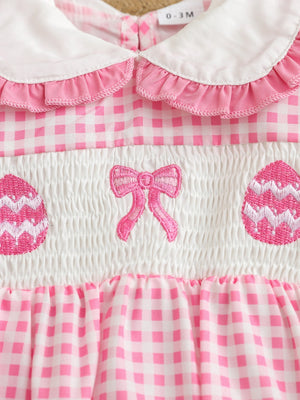 Pink gingham baby one-piece with smocking, embroidered bow, and Easter eggs.