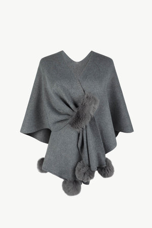 Charcoal knit cape with fur trim and pom-poms.