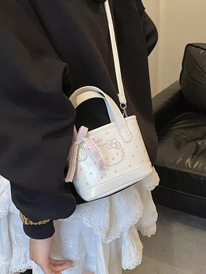 Charming mini crossbody bag in white with pink polka dots and Hello Kitty graphic, featuring a bow detail.