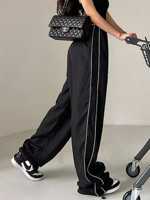 Black wide-leg maternity trousers with gathered waistband and white side stripes.