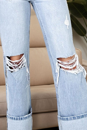 Distressed cuff wide-leg light wash denim jeans with ripped knees and frayed hem.