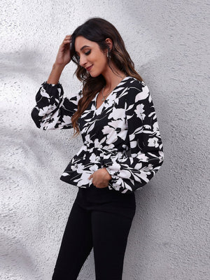 Black peplum blouse with butterfly print, gathered waist, and balloon sleeves.