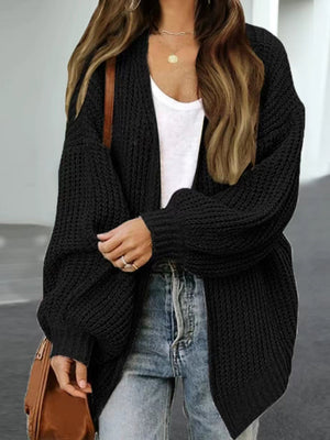 Black chunky knit cocoon cardigan with balloon sleeves and open front, worn with a white tank and jeans.