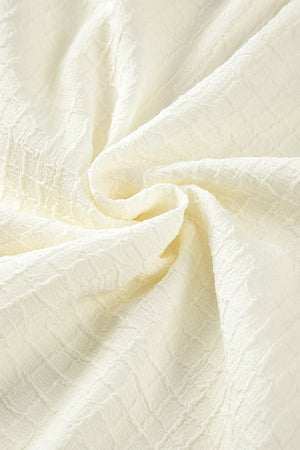 Beige voluminous blouse with textured fabric and embroidered sleeves.