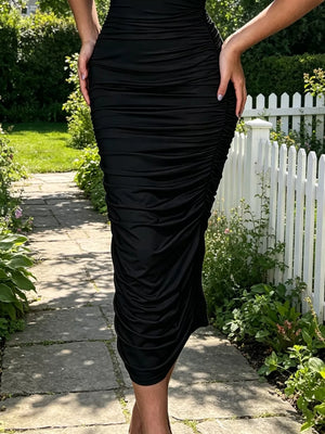 Black ruched bodycon midi dress with floral appliqué detail.