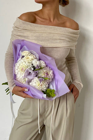 Off-the-shoulder ribbed knit top in beige with long sleeves, styled with khaki pants.