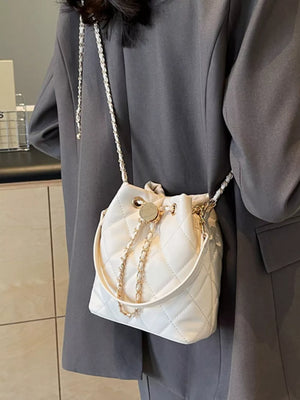 Chic quilted bucket crossbody bag in white with gold chain detail.