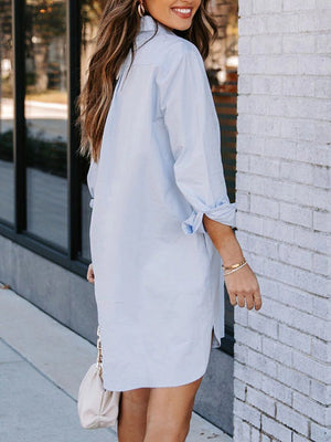 Oversized Misty Blue cotton shirt dress with curved hem and rolled sleeves.
