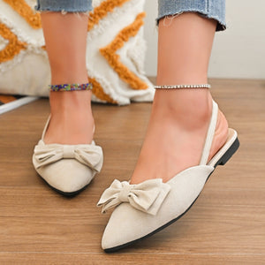 Beige slingback flats with pointed toe and bow embellishment