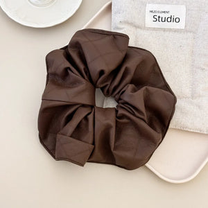 Brown quilted faux leather scrunchie with a bow detail.