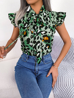 Green leopard print blouse with ruffled sleeves and pussybow tie, paired with blue jeans.
