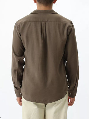 Relaxed camp collar button-up shirt in brown with back pleats and buttoned cuffs.