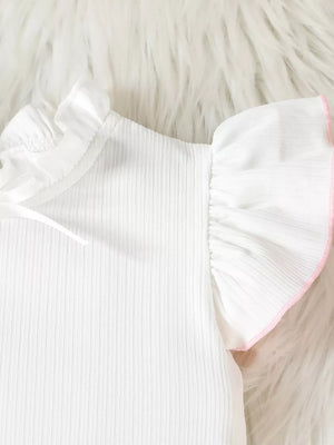 White baby top with pink trim on ruffled sleeves and neckline detail.