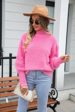 Fluffy pink mock neck sweater with balloon sleeves, styled with jeans and a handbag.