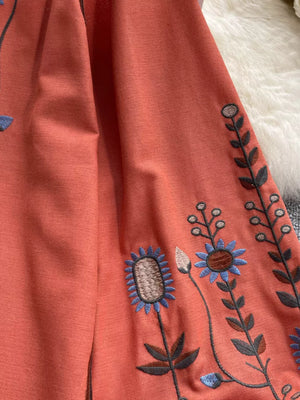 Apricot tie neck blouse with intricate floral embroidery on billowy sleeves.