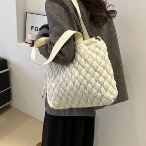 Ivory quilted drawstring carryall bag with textured pattern and fabric strap.