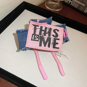 Denim patchwork claw clip with pink "THIS IS ME" patch and drawcord detail.