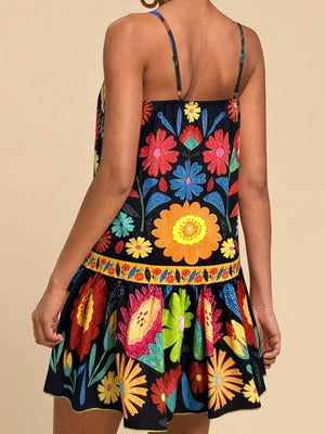 Black mini dress with vibrant floral print, spaghetti straps, and tiered skirt.