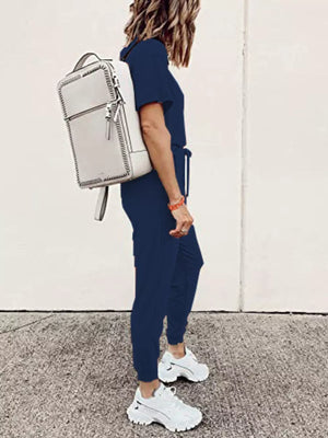 Navy blue casual round neck top and jogger pants set with drawstring waist, worn with white sneakers and a backpack.